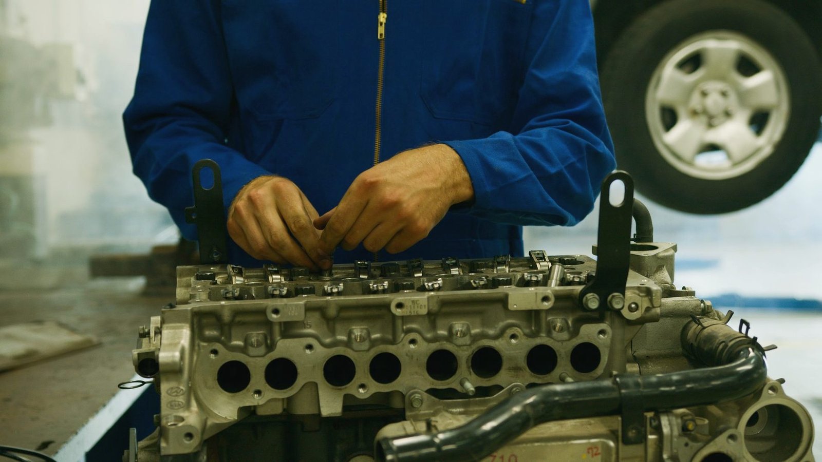 A cylinder head laid out on a bench with gloved hands alongside it.