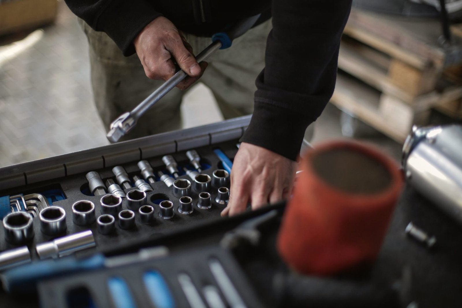 A hand selecting a socket from a set on a workbench.