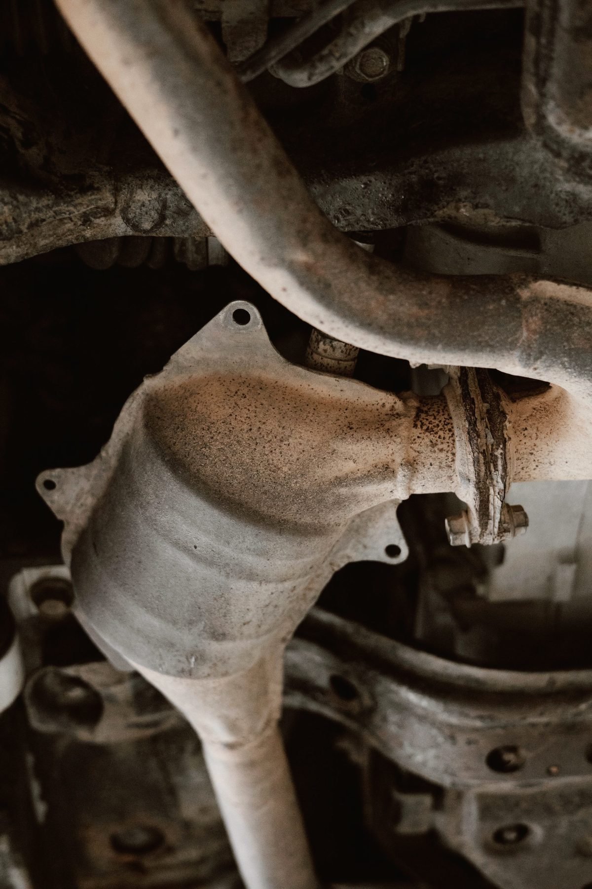 A rusted muffler and tailpipe seen from below a vehicle.