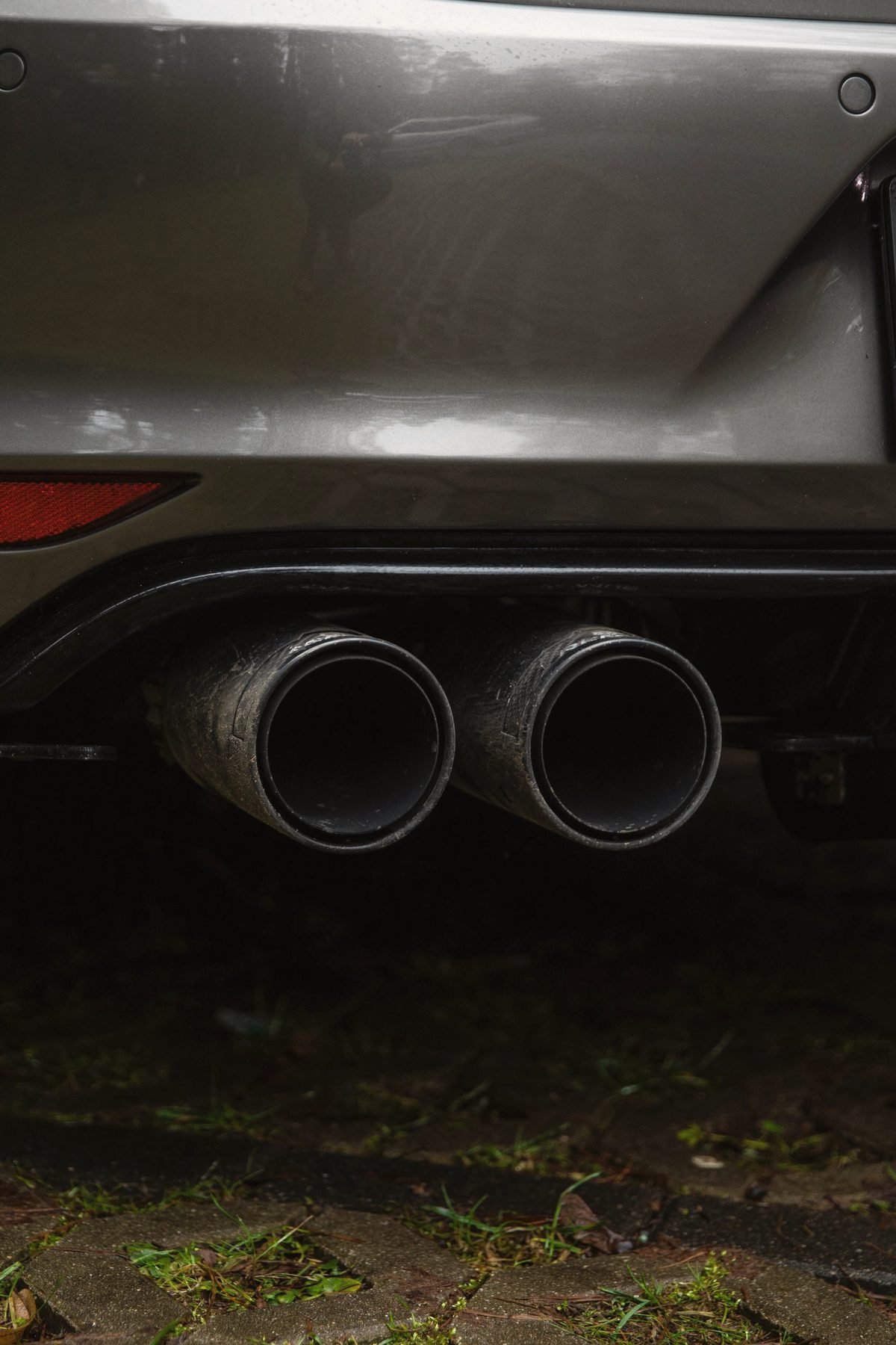 Twin tailpipes under the rear bumper of a car.