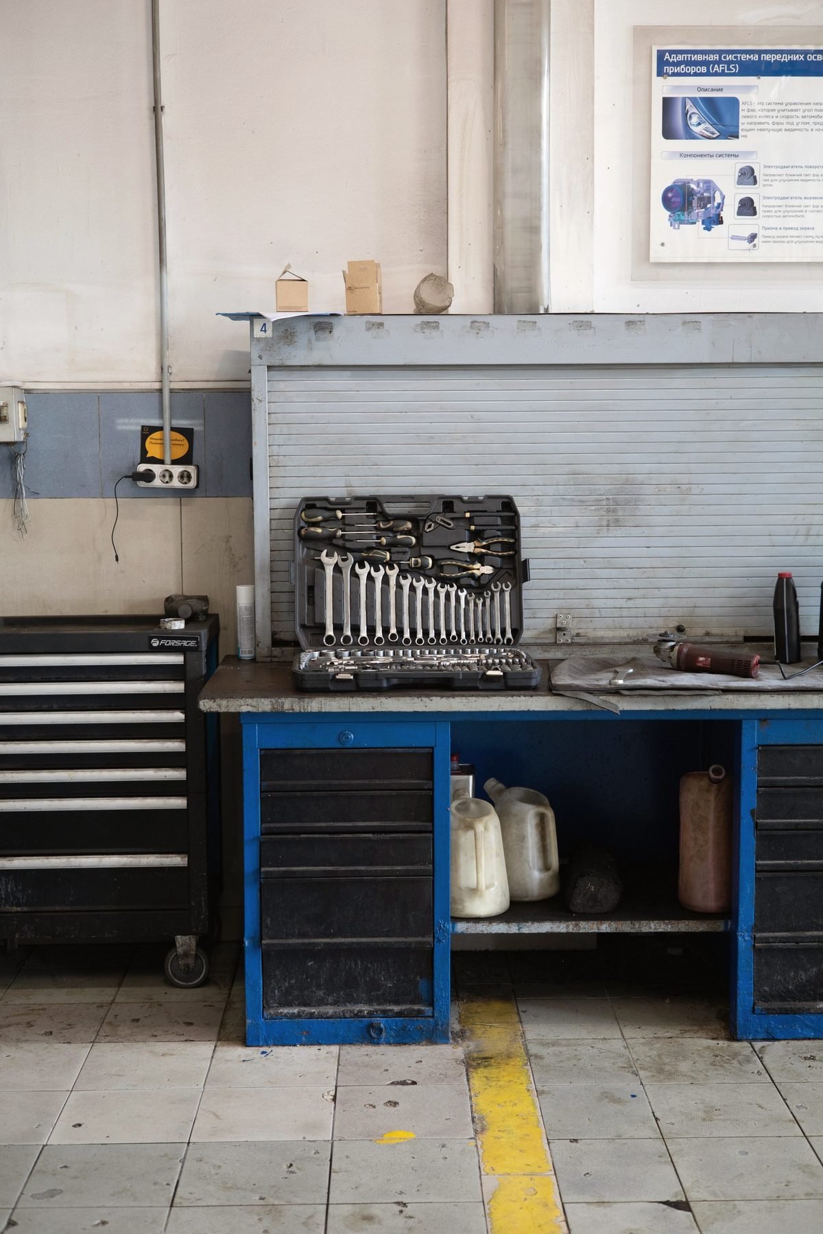 A workbench and rolling toolbox against a workshop wall.